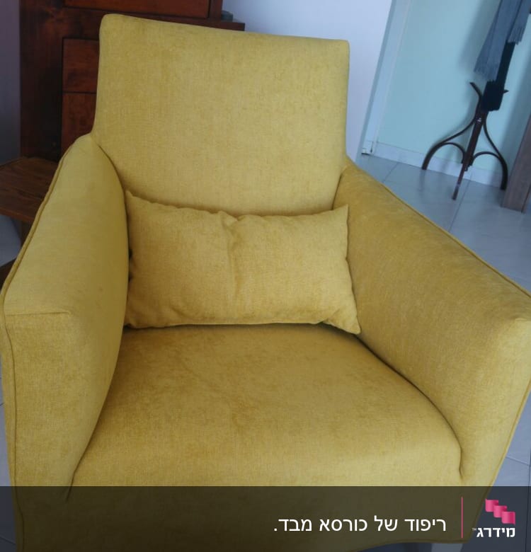 כורסה צהובה עם כרית תואמת על רצפה לבנה